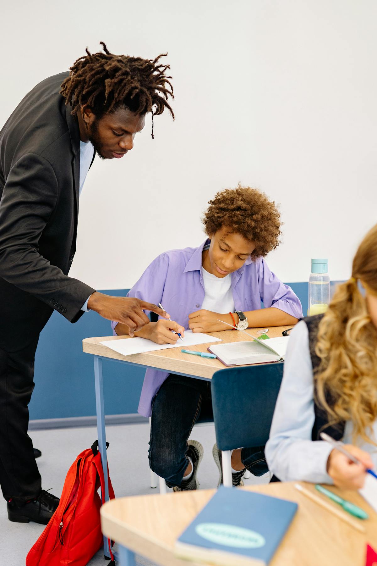 Teacher helping Black student with lesson in a classroom
