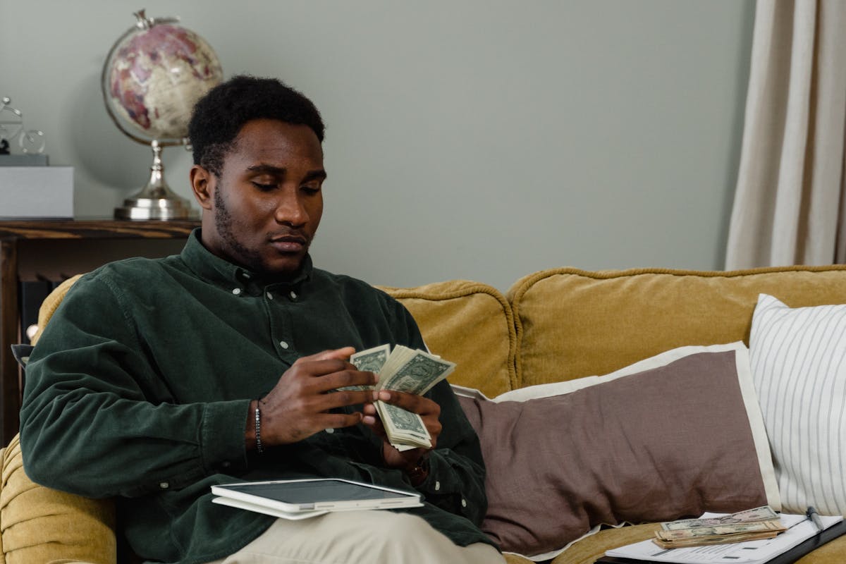 African American man carefully counting money at home